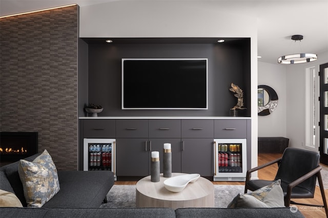 living room with beverage cooler, wood-type flooring, and a fireplace