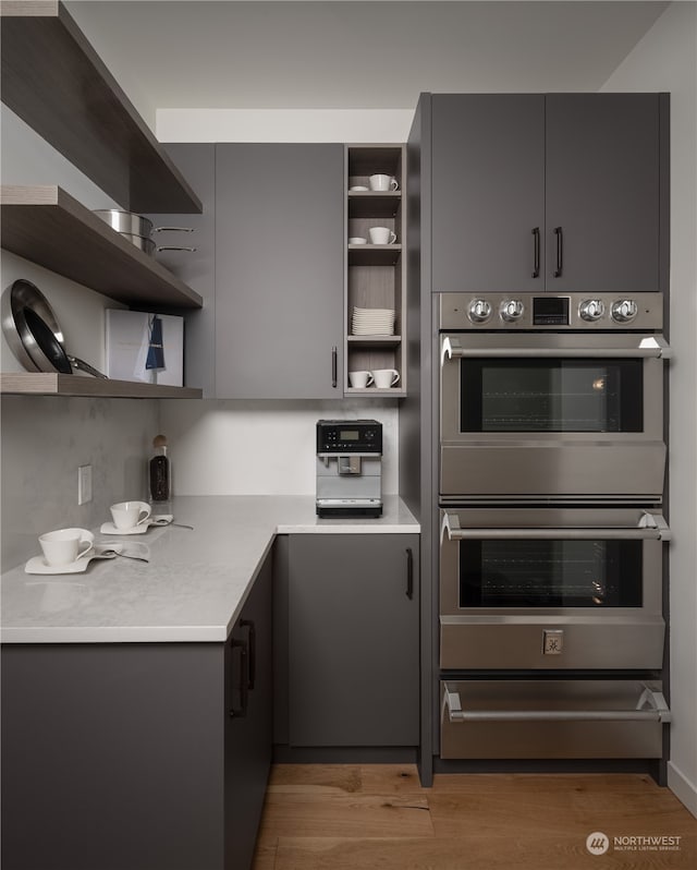 kitchen with hardwood / wood-style flooring, gray cabinetry, and stainless steel double oven