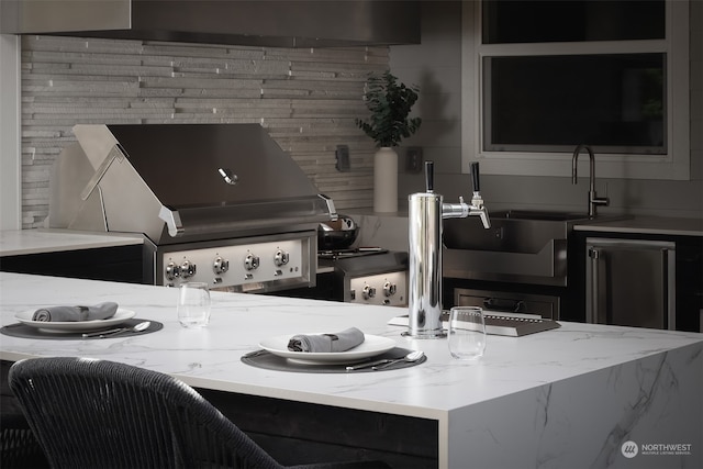 kitchen featuring sink, stainless steel refrigerator, and light stone countertops