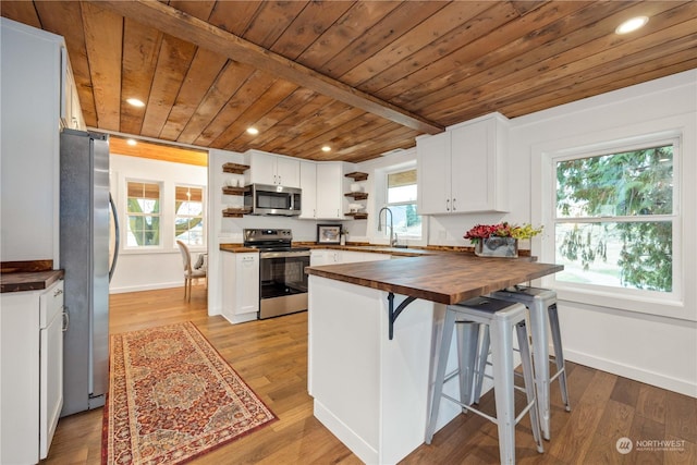 384 Washington St, Manson, WA 98831 - kitchen with stainless steel appliances, open shelves, wood counters, wooden ceiling with exposed beams, and a peninsula