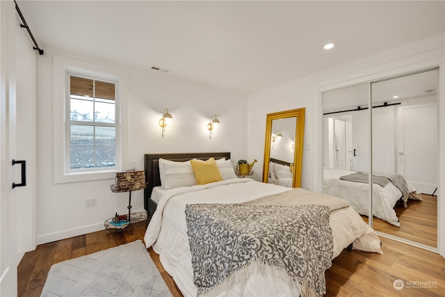 bedroom featuring a barn door, a closet, and hardwood / wood-style floors