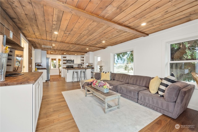 living room with light hardwood / wood-style floors, beam ceiling, and wood ceiling