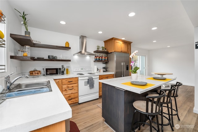 kitchen with light wood-type flooring, wall chimney range hood, stainless steel refrigerator with ice dispenser, sink, and electric range