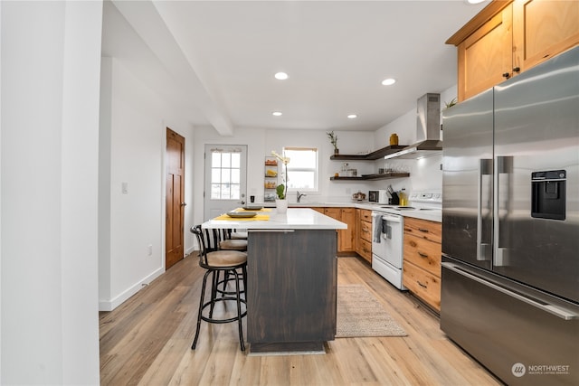 kitchen featuring a kitchen island, electric stove, high end refrigerator, wall chimney exhaust hood, and light hardwood / wood-style flooring