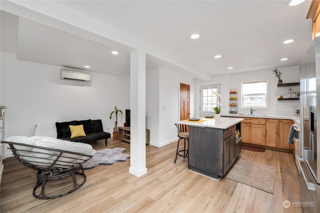 kitchen featuring light hardwood / wood-style floors, a center island, a breakfast bar, and a wall mounted air conditioner