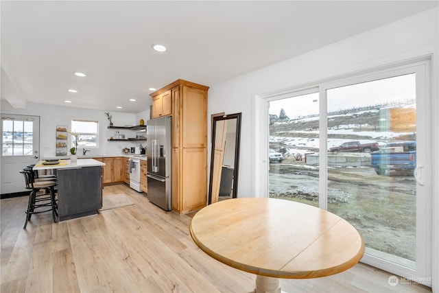 kitchen with stainless steel refrigerator with ice dispenser, plenty of natural light, and light hardwood / wood-style floors