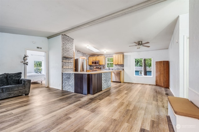 kitchen featuring ceiling fan, kitchen peninsula, light hardwood / wood-style floors, vaulted ceiling, and appliances with stainless steel finishes