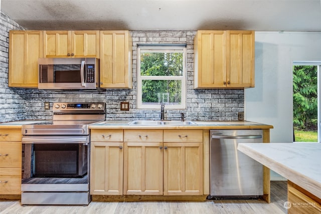 kitchen featuring sink, light hardwood / wood-style floors, light brown cabinets, and appliances with stainless steel finishes