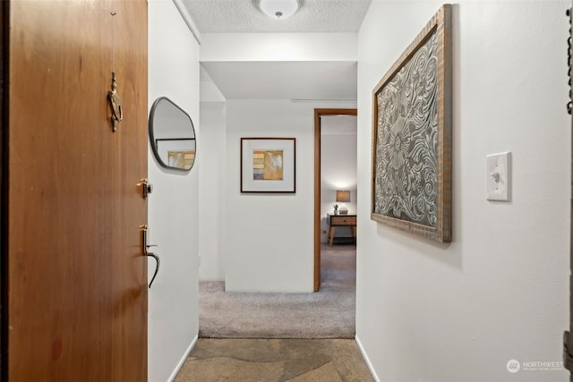 hall with carpet floors and a textured ceiling