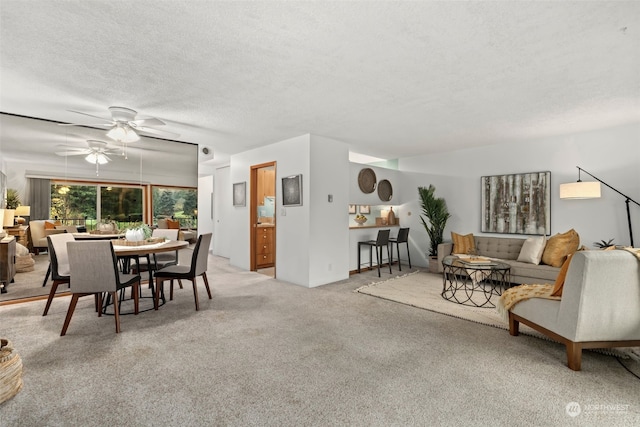 carpeted living room featuring ceiling fan and a textured ceiling