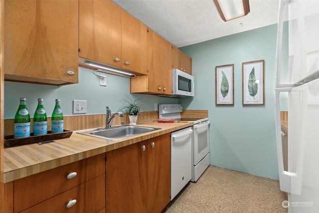 kitchen featuring a textured ceiling, white appliances, and sink