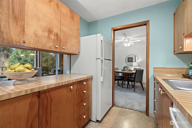 kitchen featuring a textured ceiling, white fridge, ceiling fan, and sink