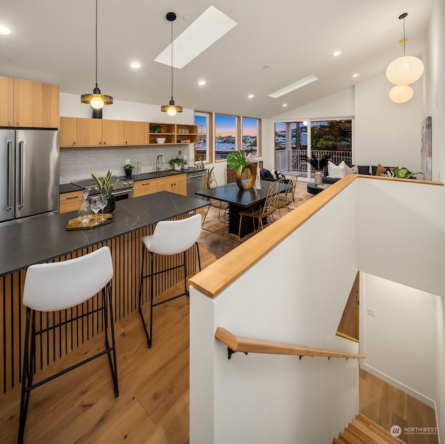 kitchen with decorative backsplash, light wood-type flooring, a breakfast bar area, and appliances with stainless steel finishes