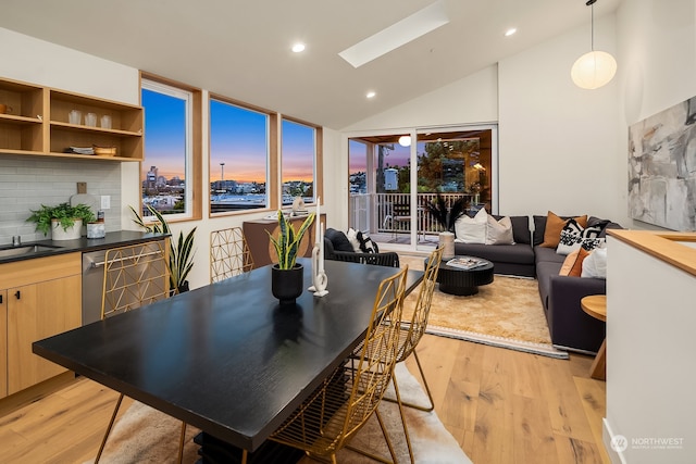 dining area featuring lofted ceiling with skylight and light hardwood / wood-style flooring