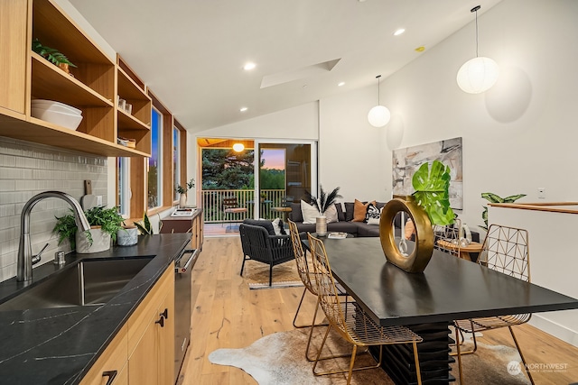 dining area featuring sink, vaulted ceiling, and light hardwood / wood-style flooring