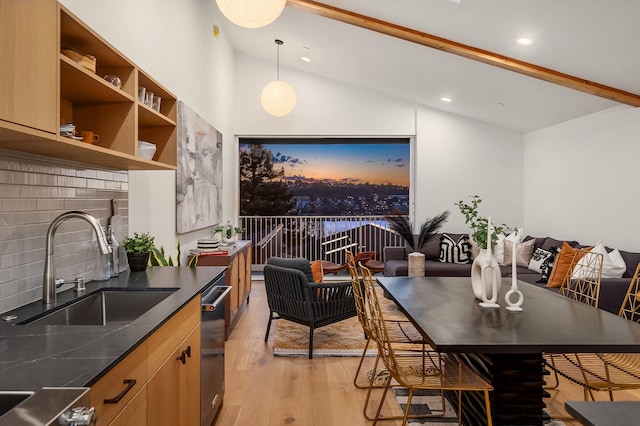 dining room with sink, lofted ceiling with beams, and light wood-type flooring