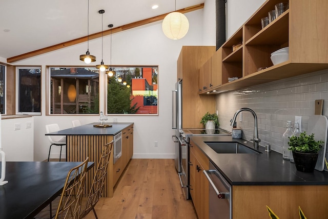 kitchen with stainless steel appliances, hanging light fixtures, sink, and vaulted ceiling with beams