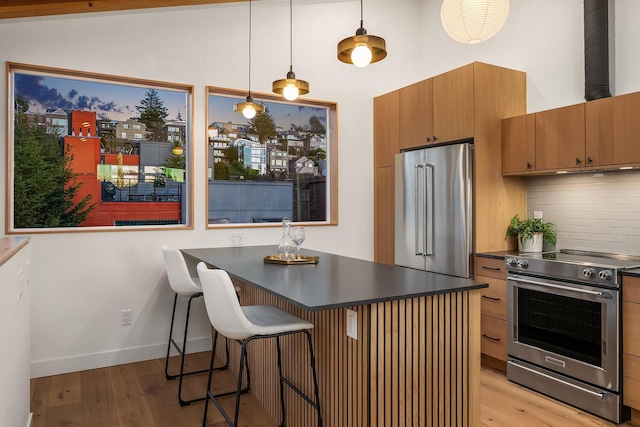 kitchen with a breakfast bar, tasteful backsplash, decorative light fixtures, light hardwood / wood-style flooring, and stainless steel appliances