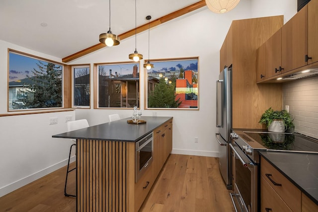 kitchen featuring pendant lighting, tasteful backsplash, lofted ceiling, a kitchen bar, and stainless steel appliances