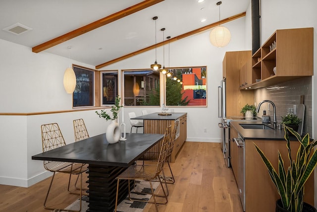 dining space with sink, vaulted ceiling with beams, and light hardwood / wood-style floors