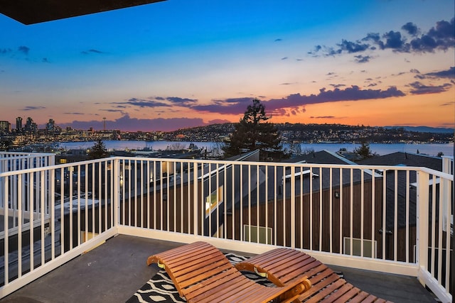 balcony at dusk featuring a water view