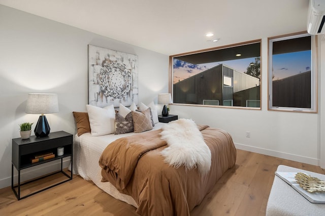 bedroom with a wall mounted air conditioner and light hardwood / wood-style floors