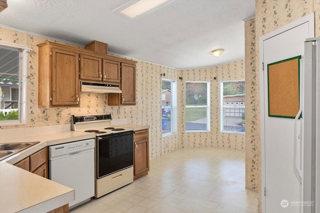 kitchen with a textured ceiling, white appliances, and crown molding