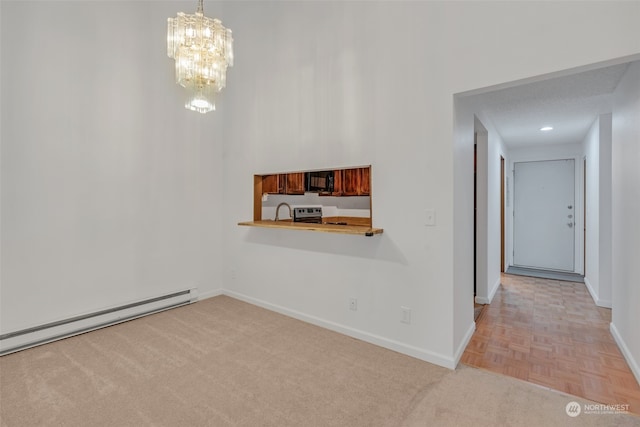 spare room featuring a textured ceiling, a baseboard heating unit, sink, a notable chandelier, and light parquet flooring