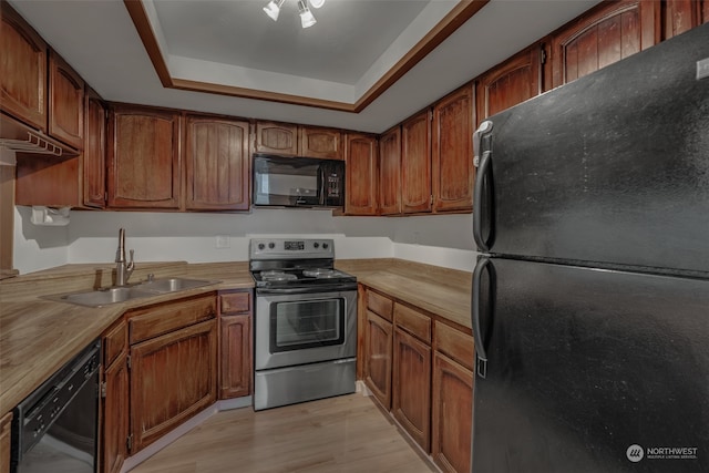 kitchen with sink, black appliances, a raised ceiling, light wood-type flooring, and butcher block countertops