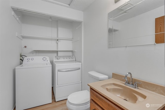 bathroom with separate washer and dryer, hardwood / wood-style floors, vanity, toilet, and a textured ceiling