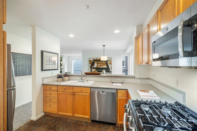 kitchen with appliances with stainless steel finishes, sink, decorative light fixtures, and dark carpet