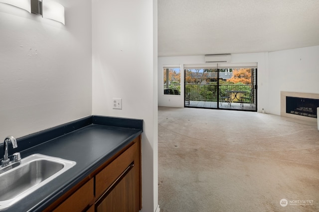 interior space featuring light carpet, a textured ceiling, a wall mounted AC, and sink