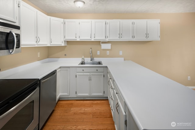 kitchen with light hardwood / wood-style floors, white cabinetry, sink, and stainless steel appliances