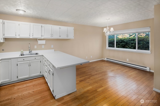 kitchen featuring a baseboard radiator, white cabinetry, hanging light fixtures, and sink