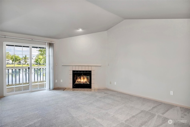 unfurnished living room featuring a tile fireplace, light carpet, a water view, and lofted ceiling