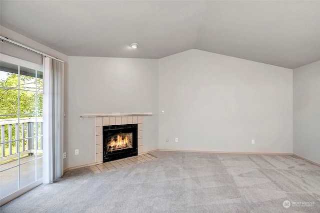 unfurnished living room featuring a tile fireplace, light colored carpet, and lofted ceiling