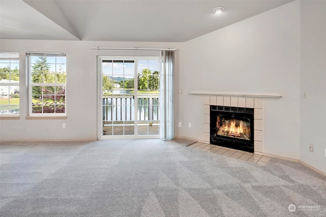 unfurnished living room featuring light carpet, a fireplace, a healthy amount of sunlight, and lofted ceiling