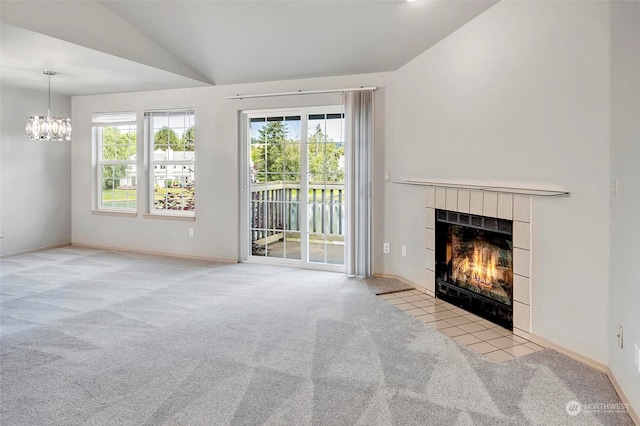 unfurnished living room with light carpet, a chandelier, vaulted ceiling, and a tiled fireplace