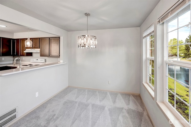 kitchen featuring electric stove, light colored carpet, decorative light fixtures, and an inviting chandelier