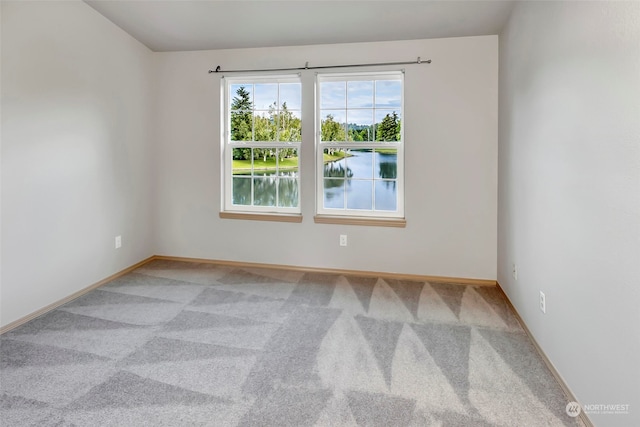 unfurnished room with carpet flooring and a water view