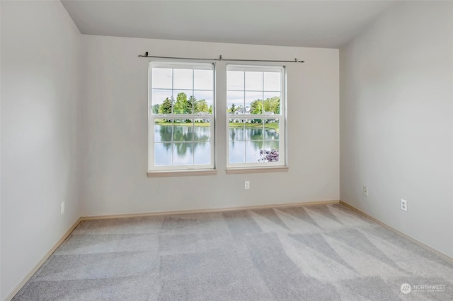 spare room featuring a water view and light colored carpet