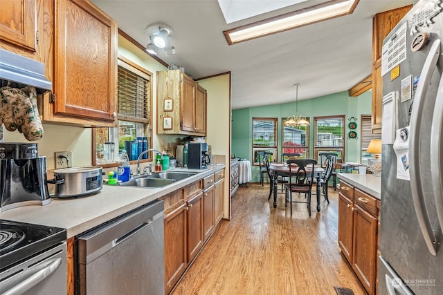 kitchen with sink, light hardwood / wood-style flooring, vaulted ceiling, decorative light fixtures, and appliances with stainless steel finishes