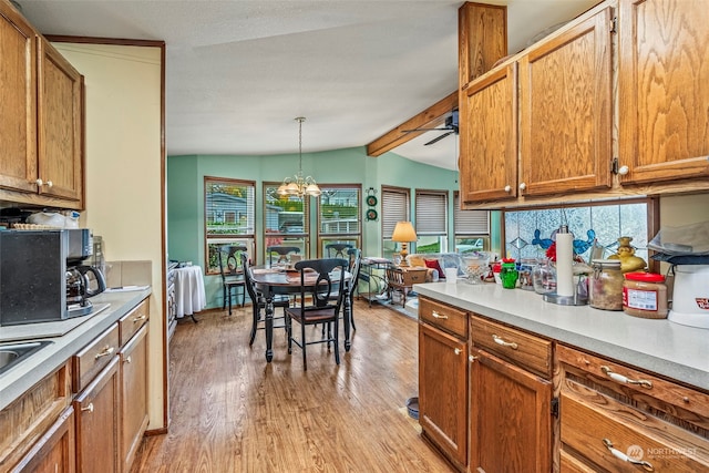 kitchen with vaulted ceiling with beams, plenty of natural light, decorative light fixtures, and light wood-type flooring