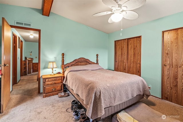 carpeted bedroom with beamed ceiling and ceiling fan