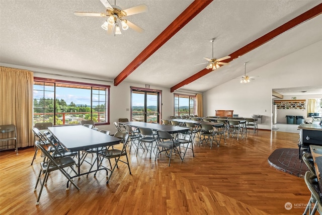 dining area featuring a textured ceiling, lofted ceiling with beams, light hardwood / wood-style floors, and ceiling fan