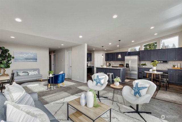 living room with light hardwood / wood-style flooring, vaulted ceiling, and sink