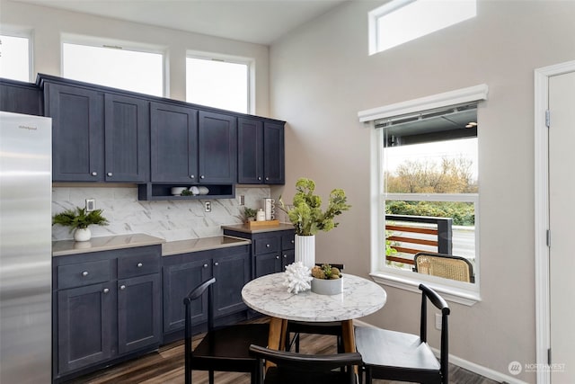 kitchen with tasteful backsplash, stainless steel fridge, blue cabinetry, and dark wood-type flooring