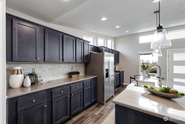 kitchen with backsplash, sink, stainless steel refrigerator with ice dispenser, hanging light fixtures, and dark hardwood / wood-style flooring