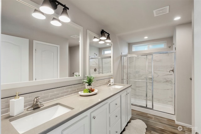 bathroom featuring tasteful backsplash, hardwood / wood-style floors, vanity, and a shower with door