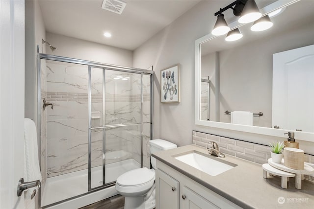 bathroom featuring vanity, backsplash, toilet, an enclosed shower, and wood-type flooring